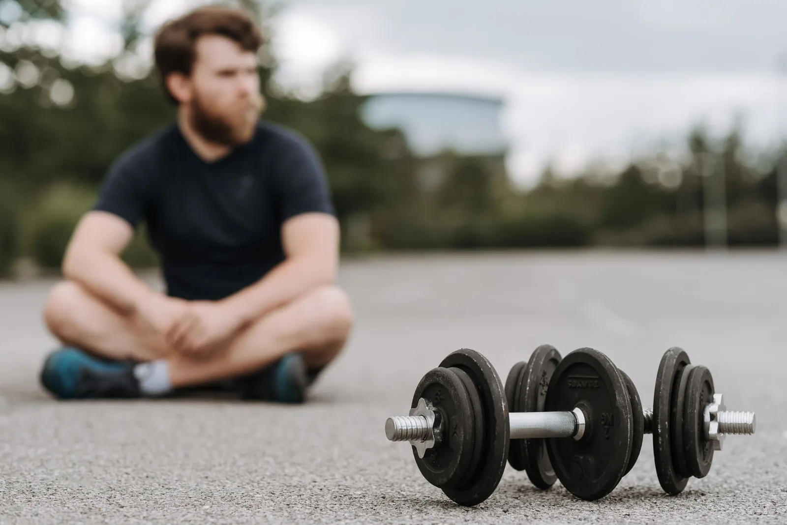 Adjustable dumbbell set beside fixed hex dumbbells on a rubber gym floor, showing the size difference