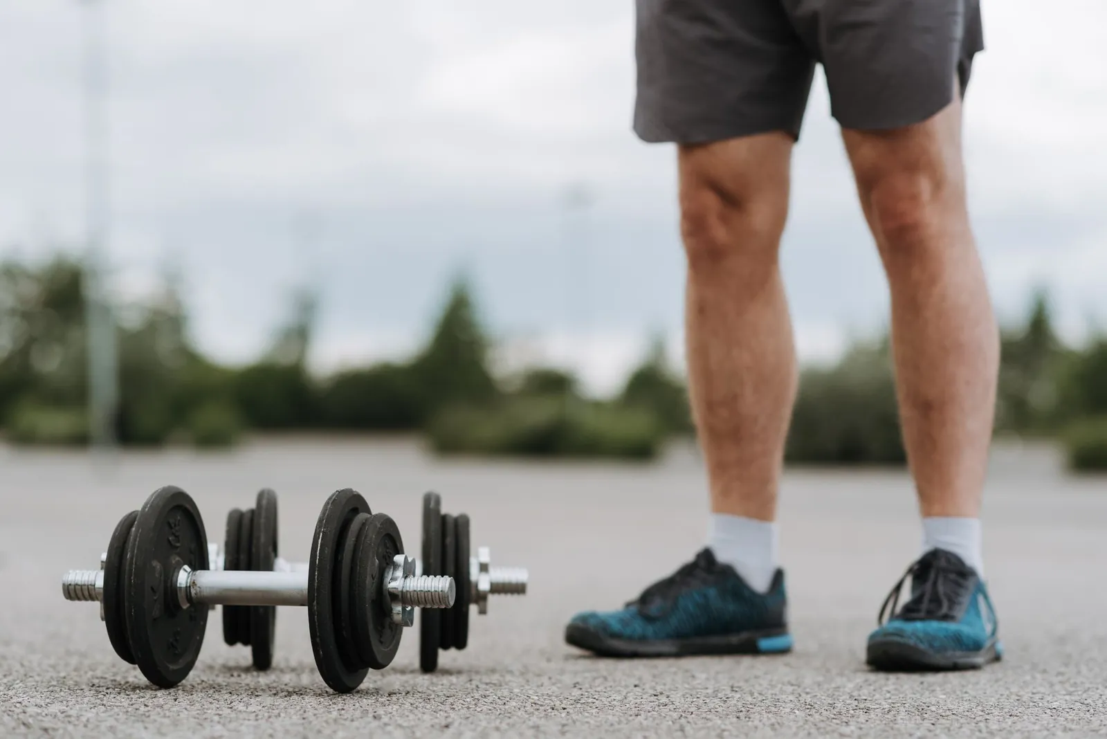 Close-up of a hand rotating a dial-style adjustable dumbbell to change weight before a set