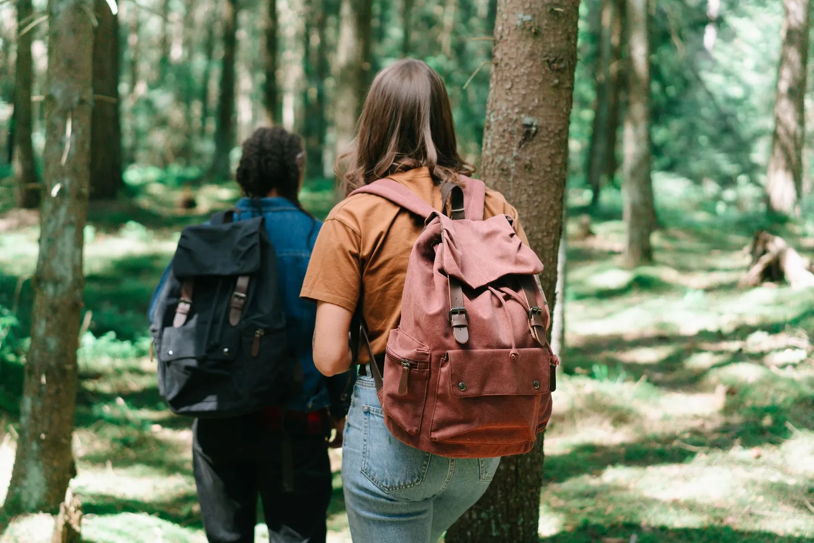 Beginner backpacker adjusting hip belt and shoulder straps on a 60-liter backpacking pack at a trailhead