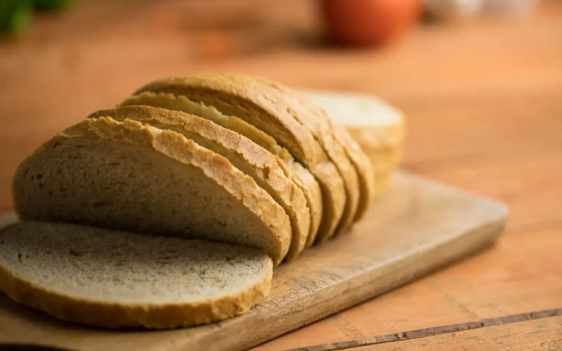 Oats, brown rice, sweet potatoes, bananas, and whole grain bread arranged by glycemic speed on a wooden surface