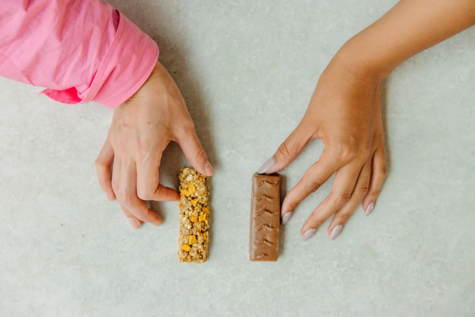 Seven energy bars including Clif, Maurten, RXBAR, and Built Bar lined up on a wooden surface showing packaging and size differences