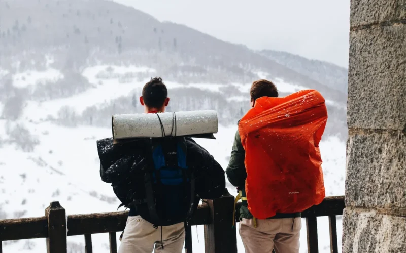 Hiker wearing broken-in mid-cut hiking boots and a fitted 25L daypack on a rocky forest trail