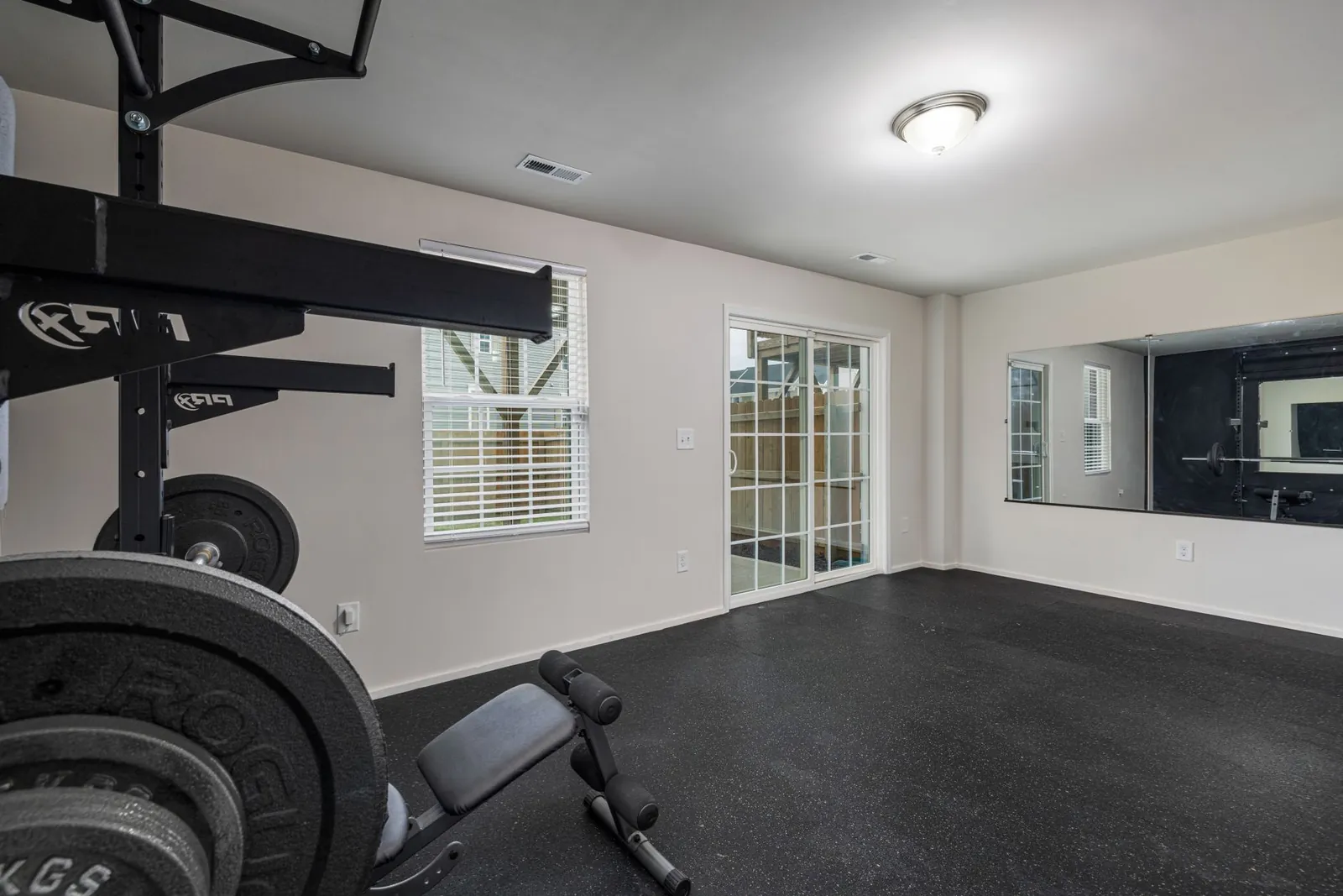 Five resistance loop bands arranged by thickness next to a rolled-out yoga mat in a spare room home gym