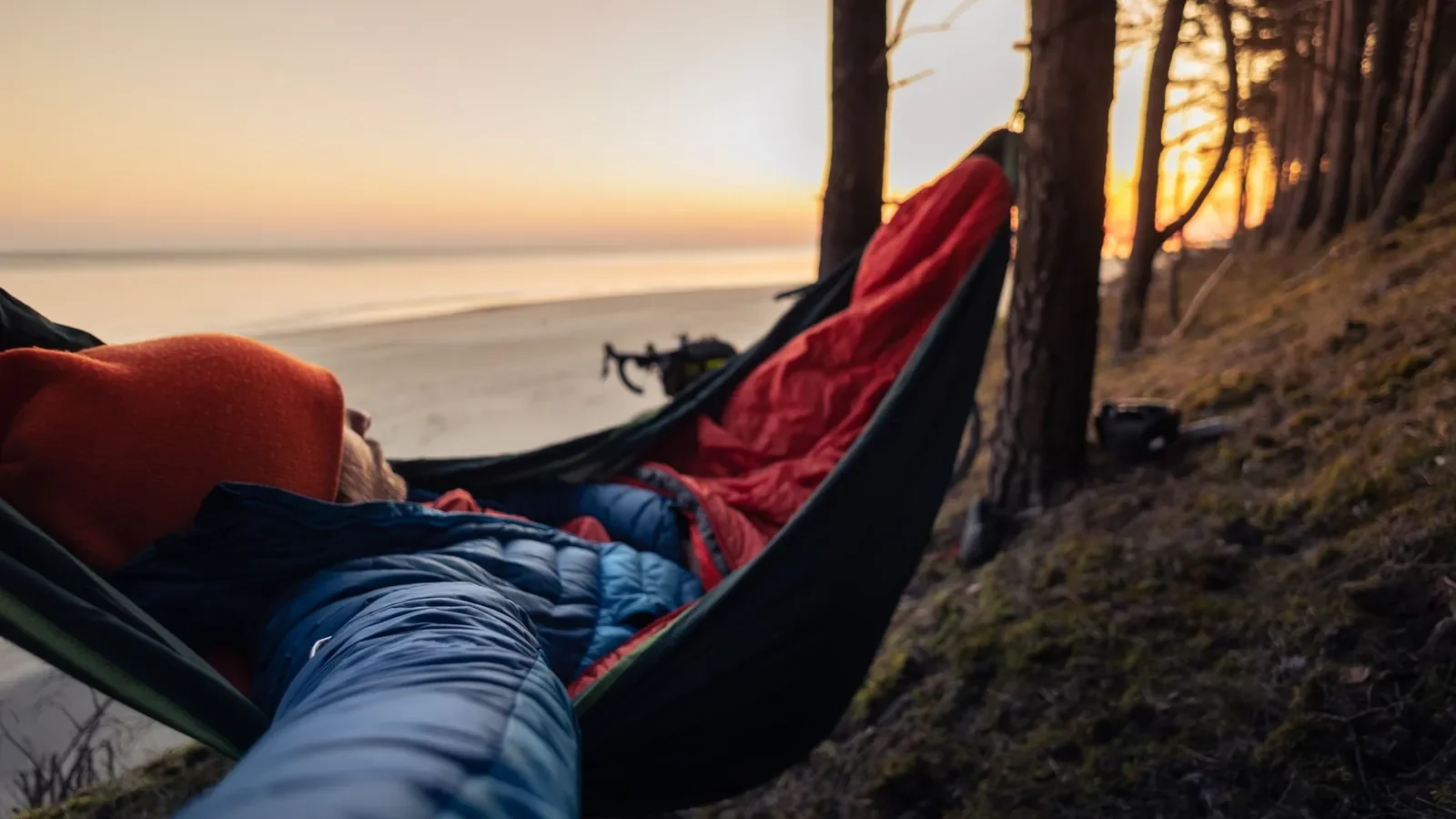 Mummy-shaped cold weather sleeping bag laid flat showing cinched hood and insulated draft collar at the neck opening
