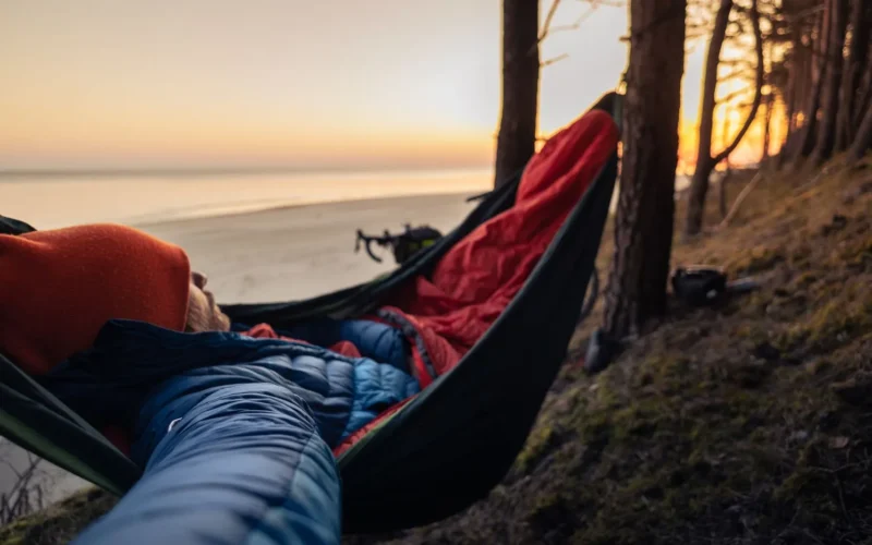 Mummy-shaped cold weather sleeping bag laid flat showing cinched hood and insulated draft collar at the neck opening