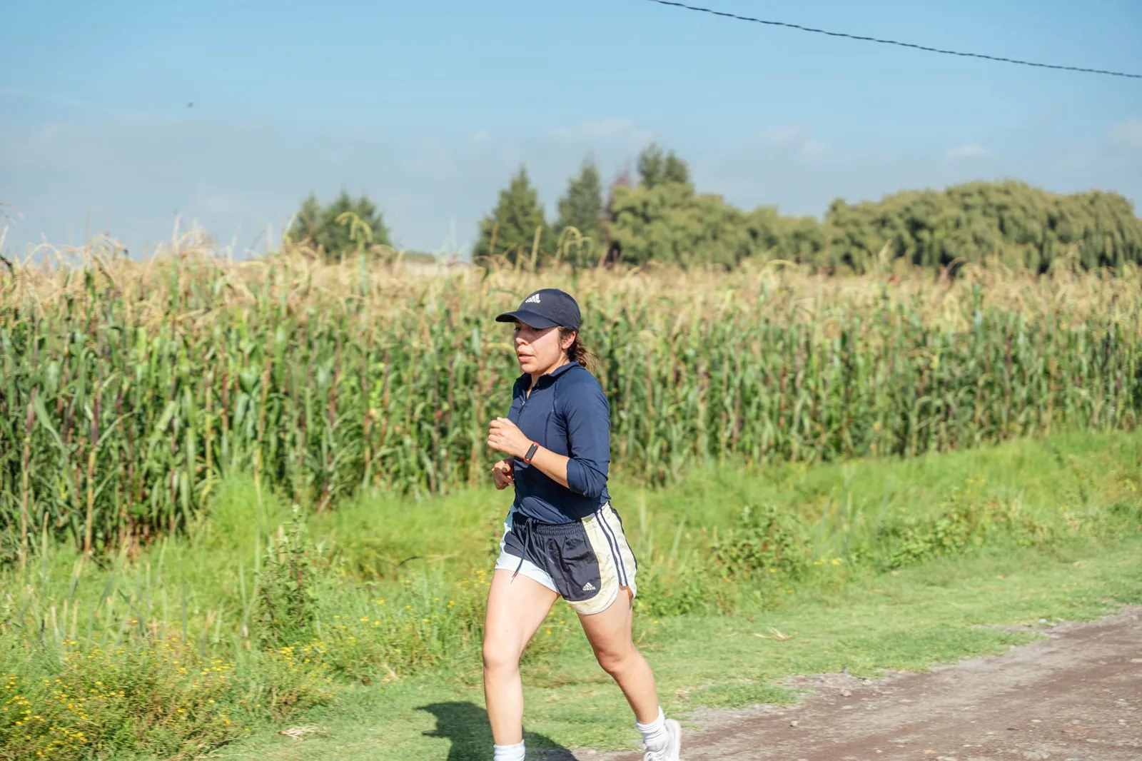 Runner in athletic wear jogging on a park path during daytime with trees in background