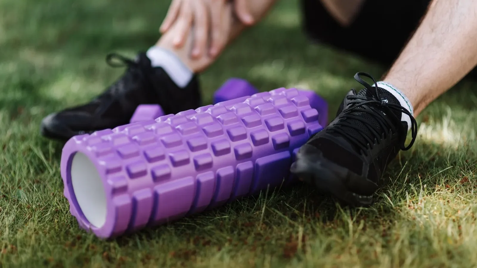 Athlete foam rolling their quad on a gym floor, body weight controlling pressure on the muscle