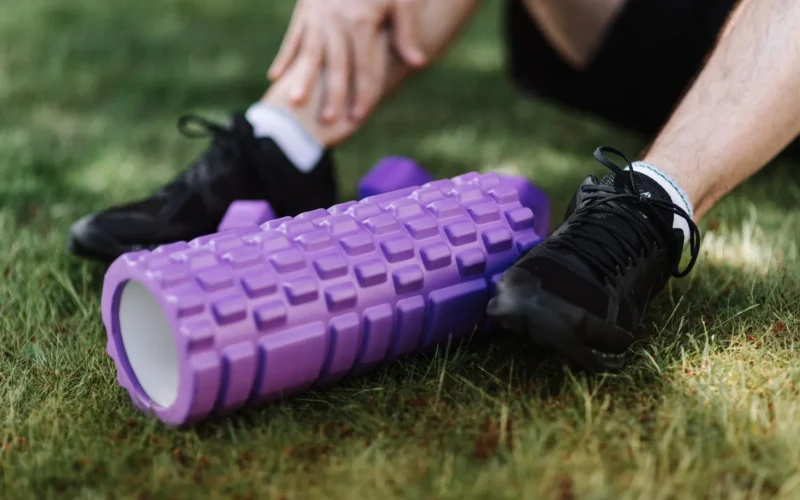 Athlete foam rolling their quad on a gym floor, body weight controlling pressure on the muscle