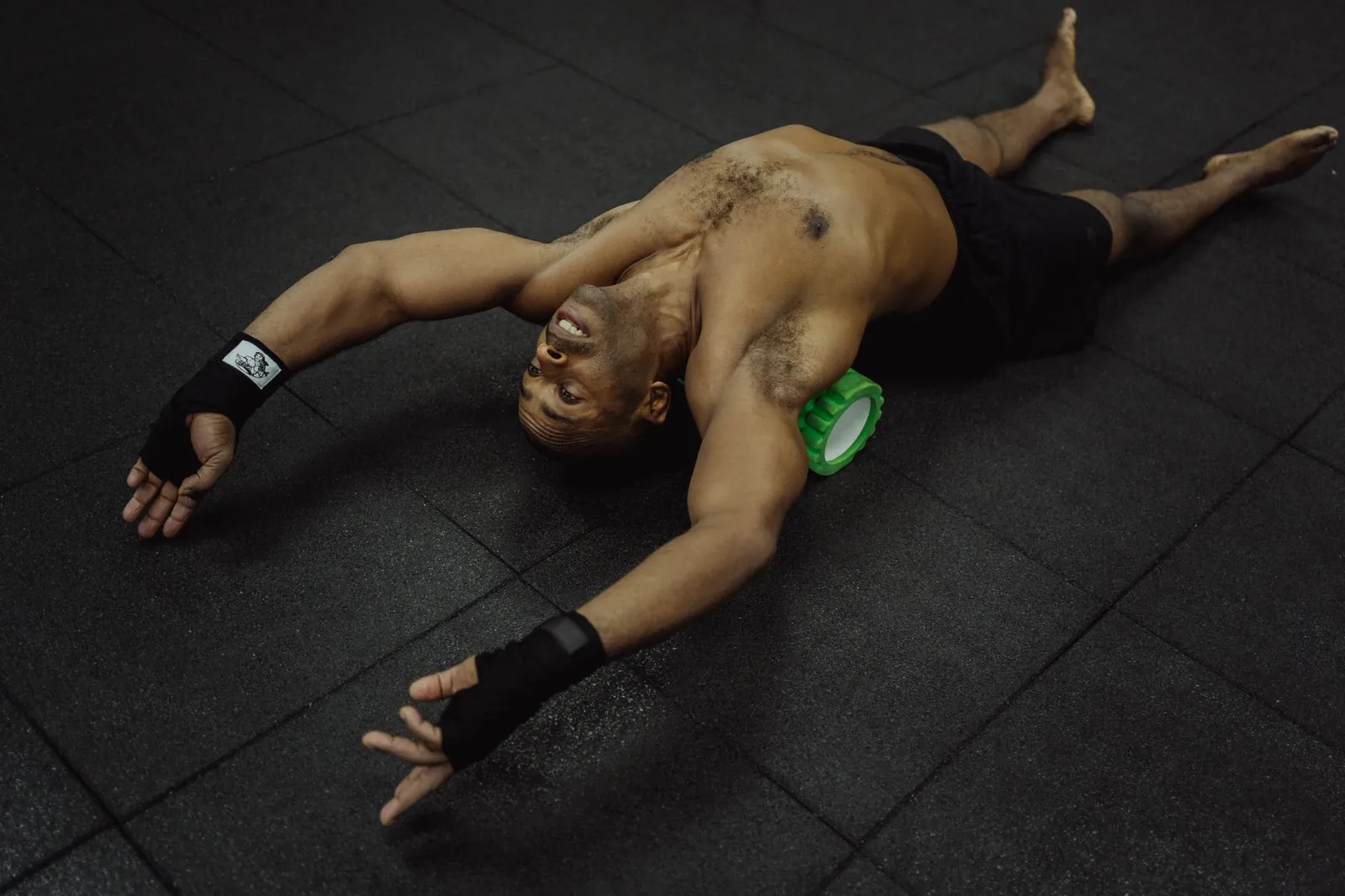 Athlete foam rolling their quad on a gym floor, body weight controlling pressure on the muscle