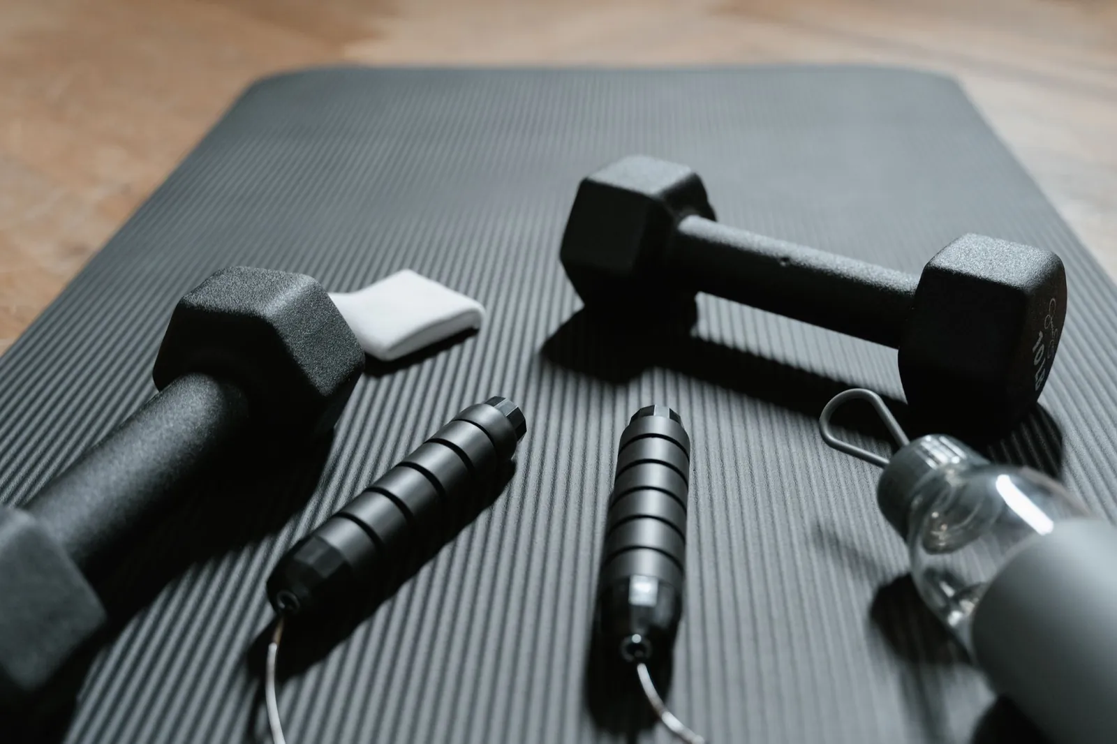 Adjustable dumbbells and resistance bands arranged on a yoga mat for a home full body workout