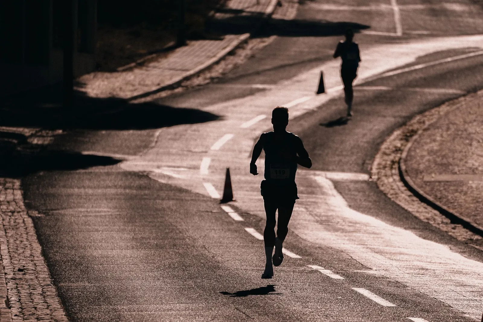Runner on an open road at dawn maintaining upright posture and midfoot strike during a long training run