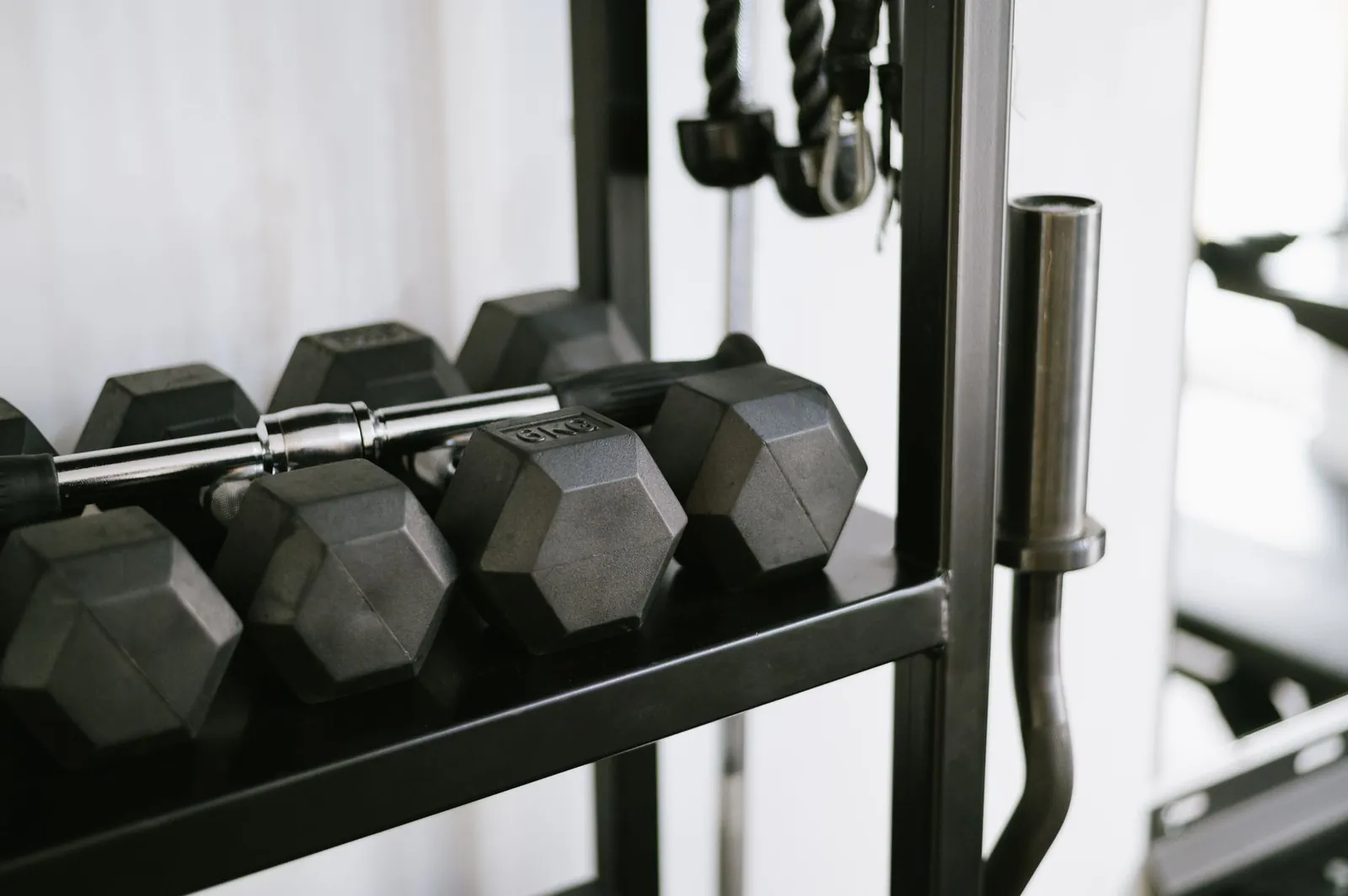 Adjustable dumbbells, resistance loop bands, and doorway pull-up bar arranged on a foam mat in a home gym corner