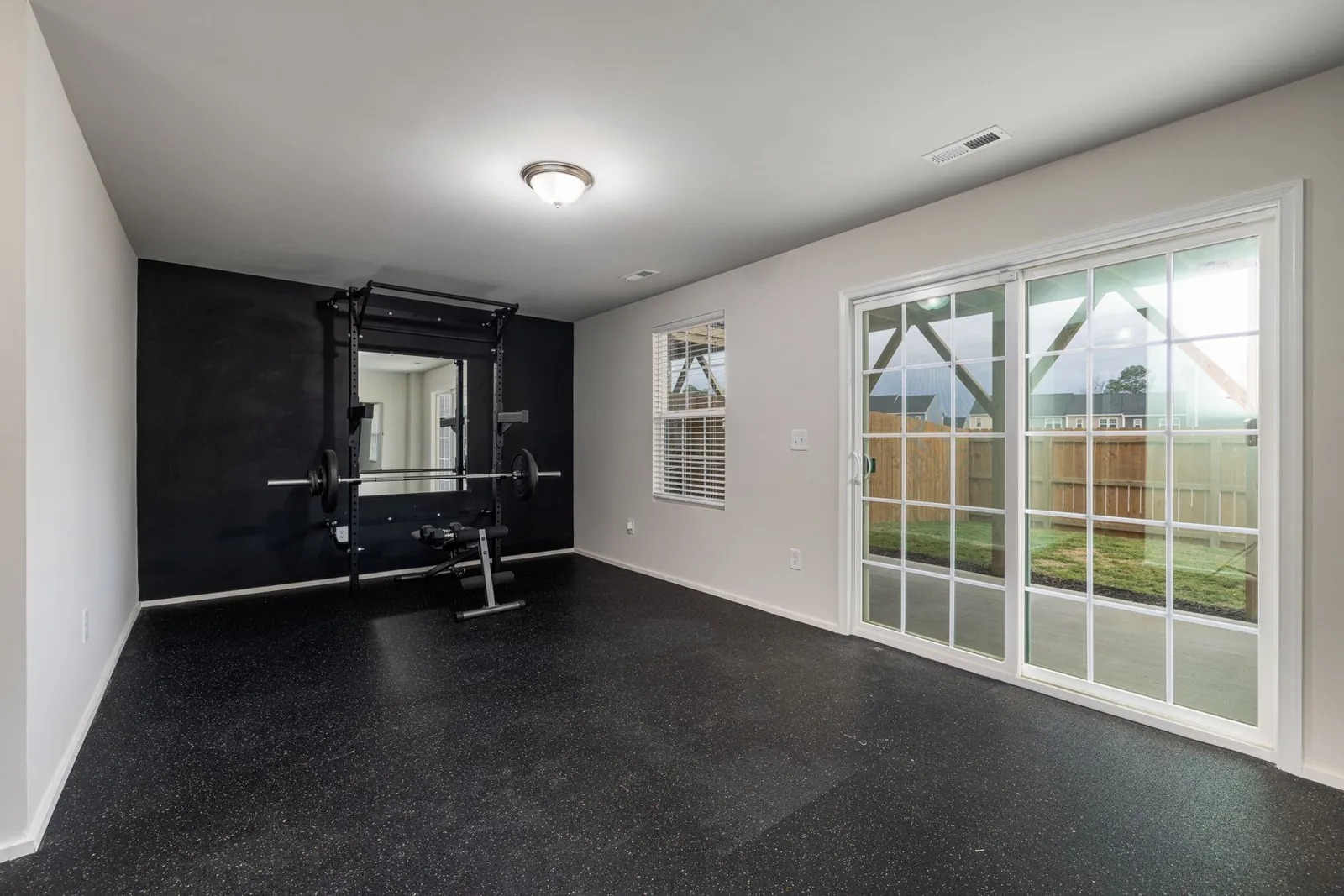 Flat weight bench with dumbbells and interlocking foam floor tiles in a compact home gym setup