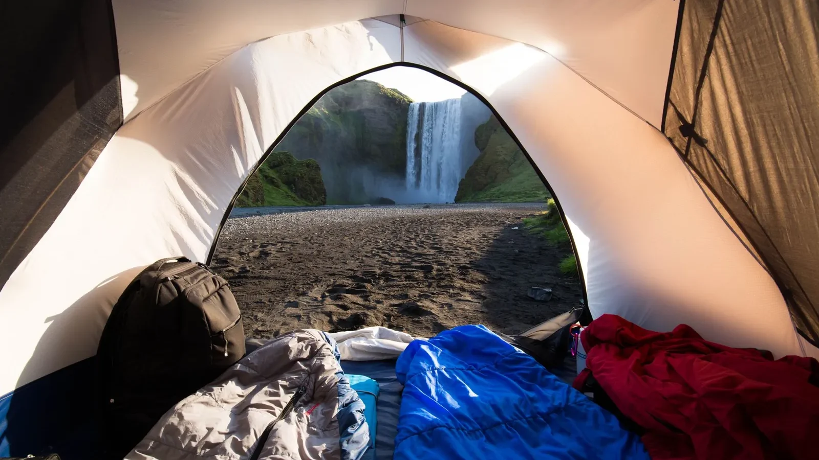 Sleeping bags sorted by temperature rating on a tent floor, showing down and synthetic options side by side