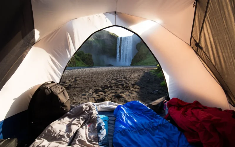 Sleeping bags sorted by temperature rating on a tent floor, showing down and synthetic options side by side