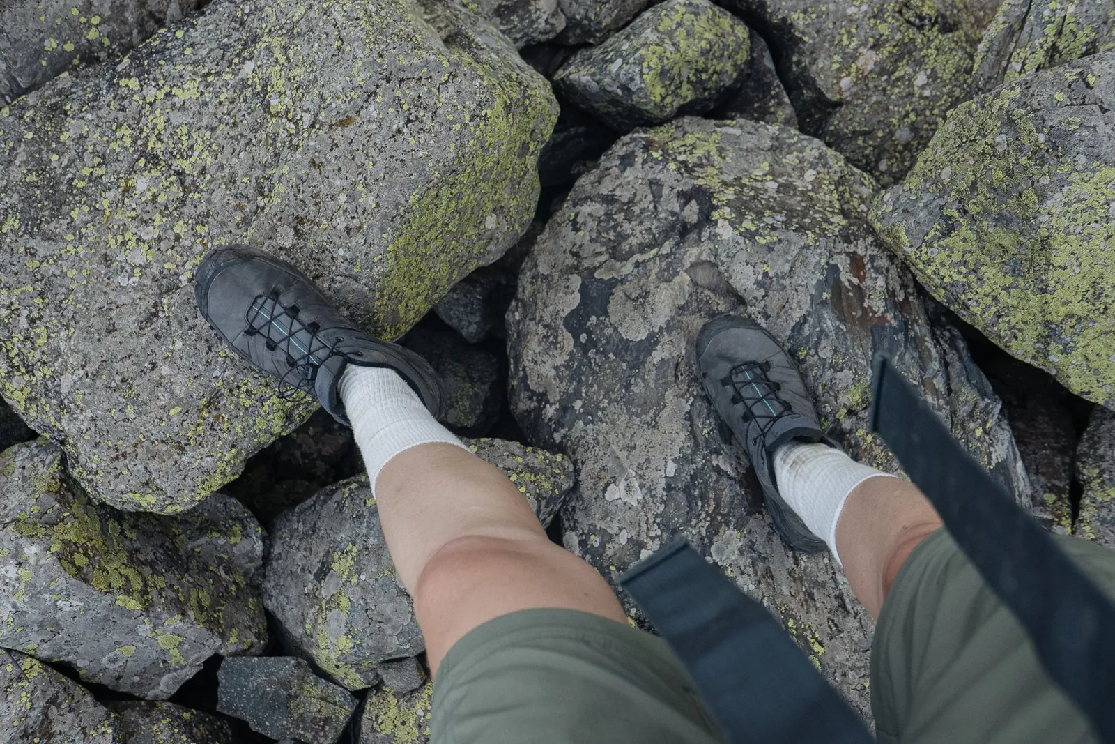 Close-up of a boot fit test showing one thumb-width of toe room and snug heel contact with hiking socks on