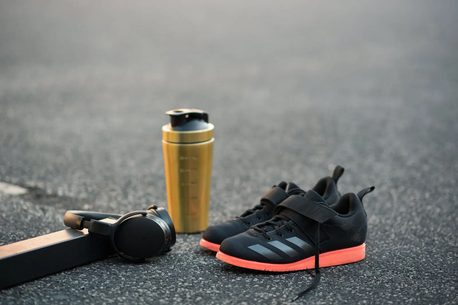 Massage gun, compression boots, and smart foam roller laid out on a gym floor beside a training log