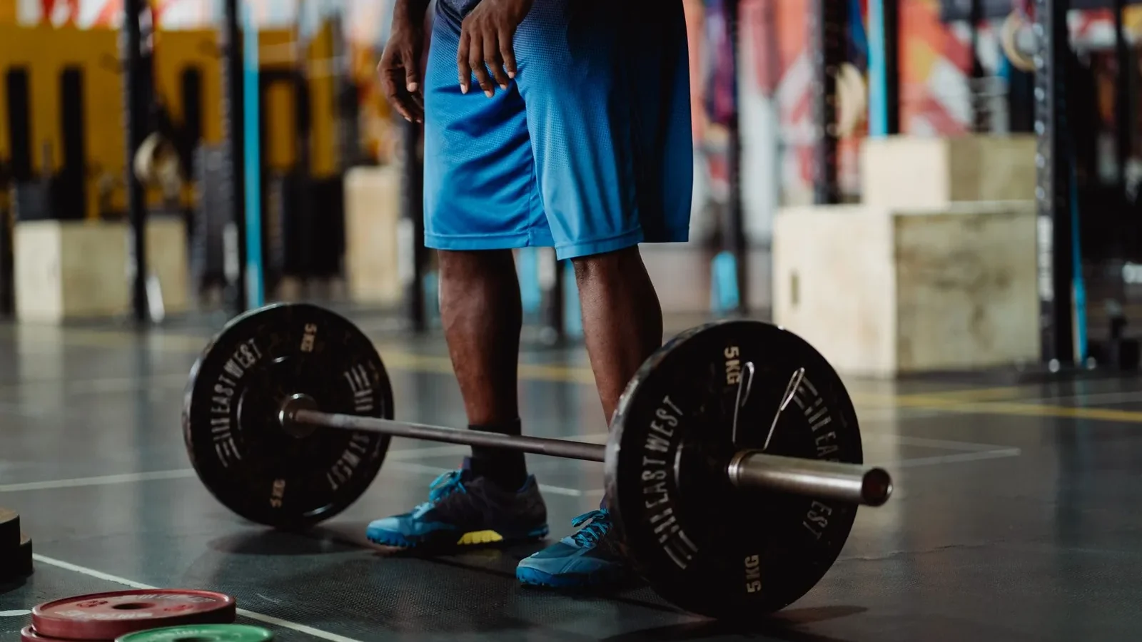 Lifter adding a 5-pound plate to a loaded barbell before a squat set