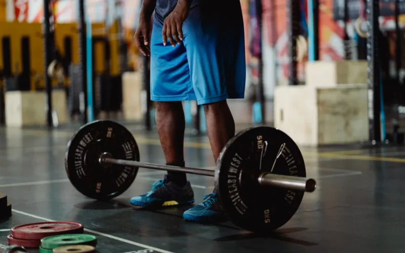 Lifter adding a 5-pound plate to a loaded barbell before a squat set