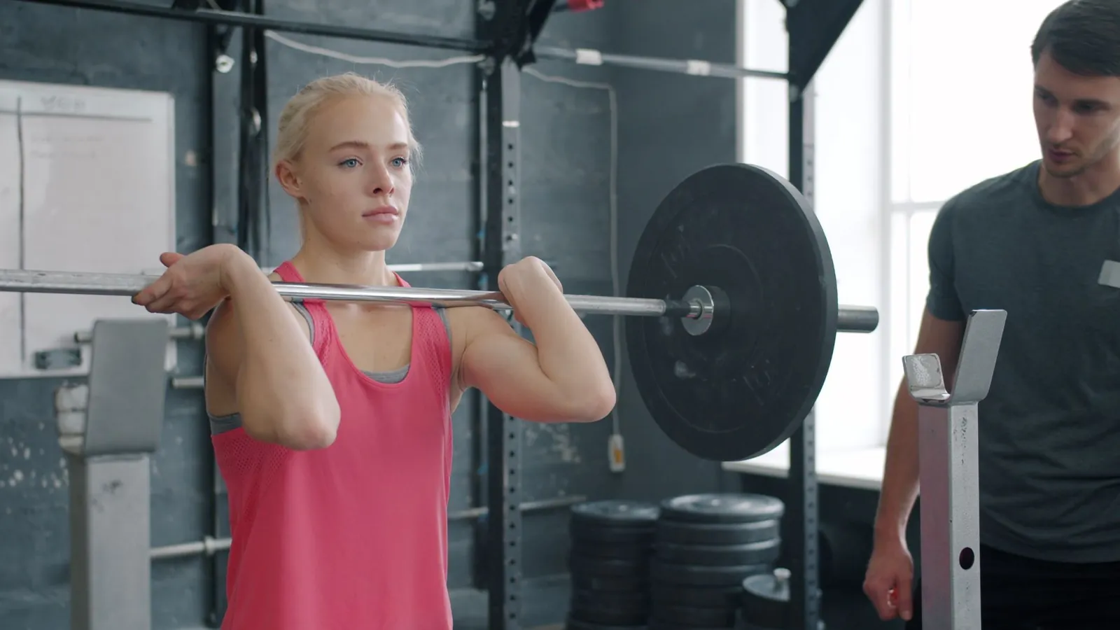 Lifter adding a 5-pound plate to a loaded barbell before a squat set