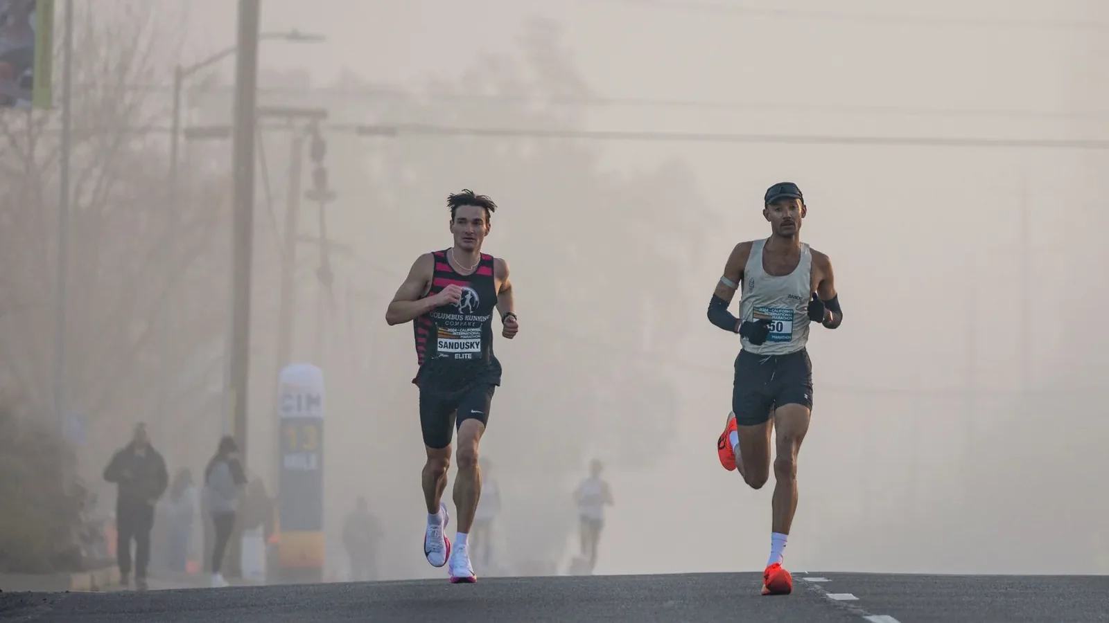 Runners crossing the finish line at a spring marathon in April morning light