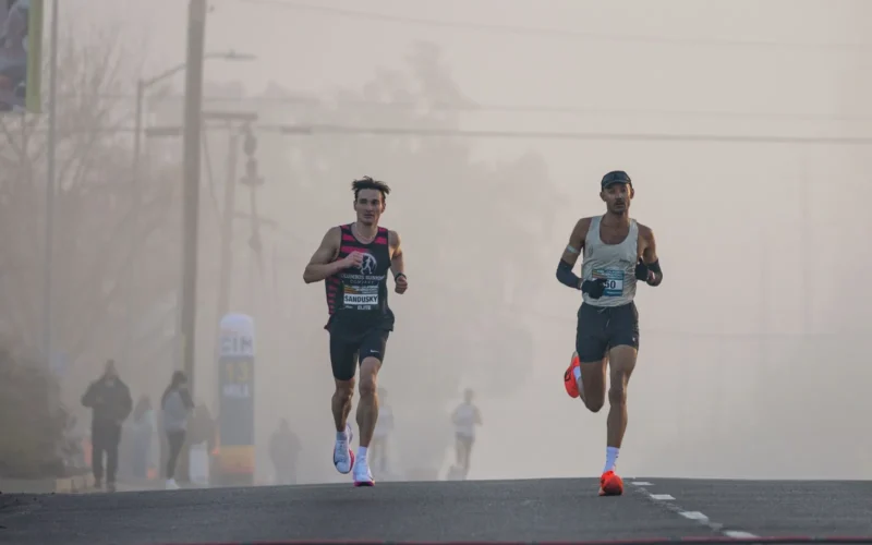 Runners crossing the finish line at a spring marathon in April morning light
