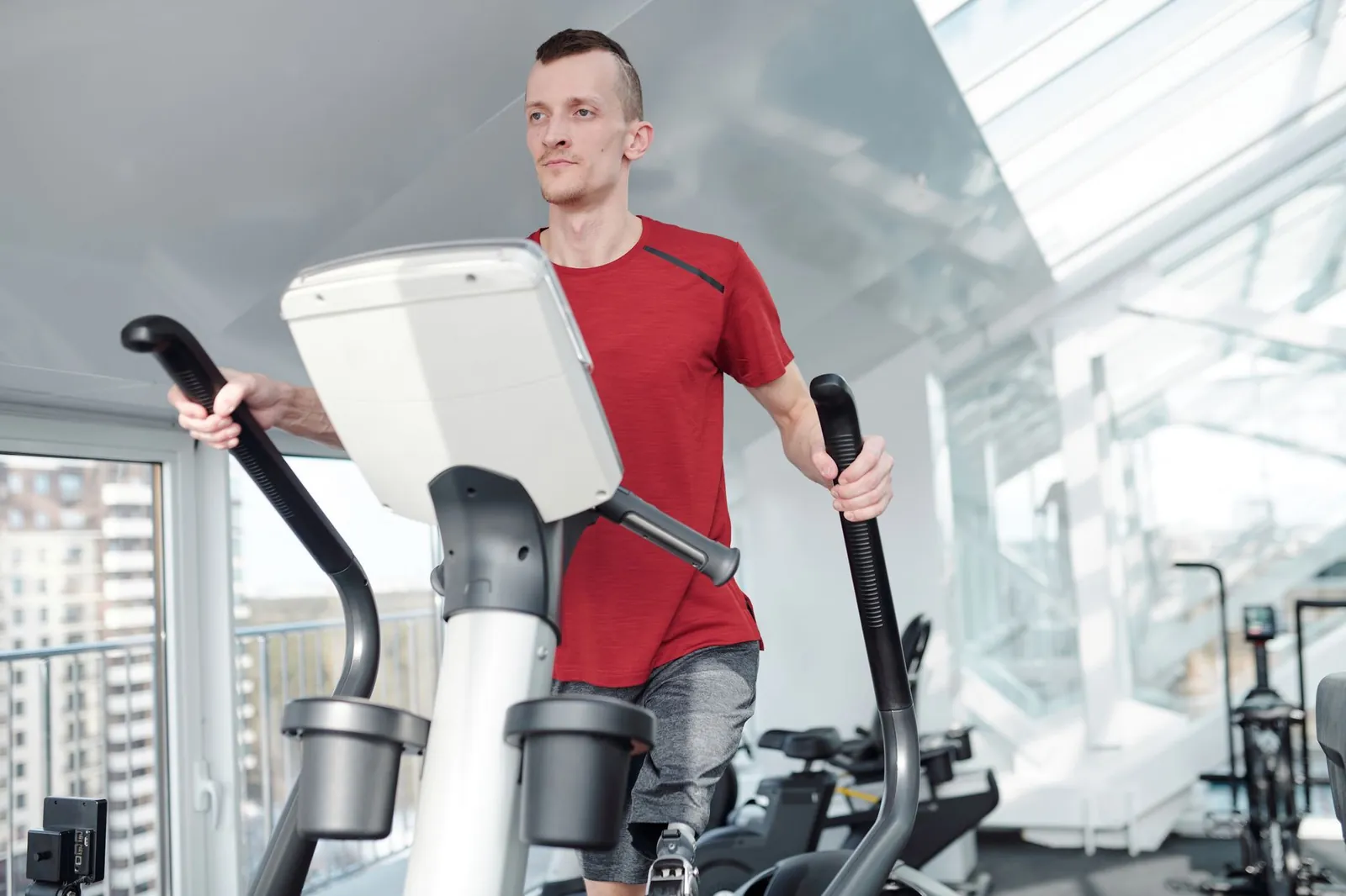 Treadmill and elliptical machine side by side in a home gym with wood flooring and natural light