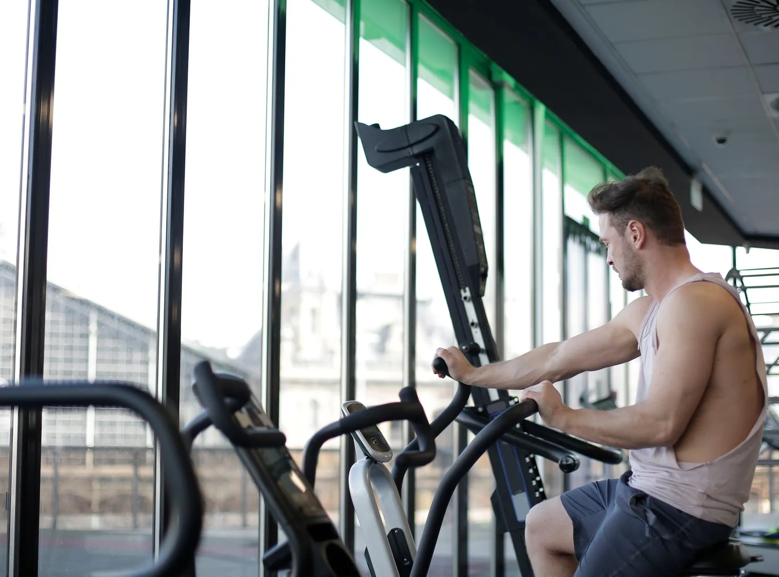 Person on an elliptical machine actively gripping and pushing the moving handles with upright posture